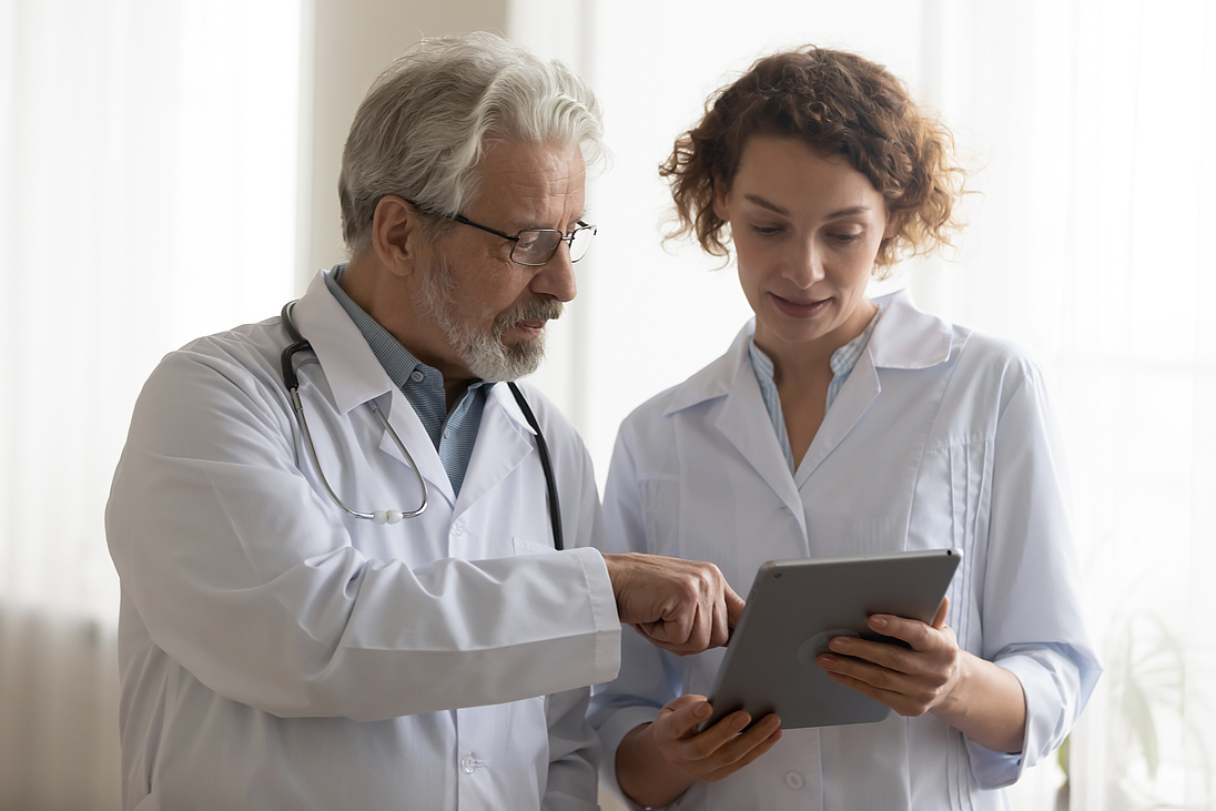 Medical team of two professional doctors talking using digital tablet