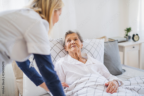 Eine Pflegerin versorgt eine ältere Frau in deren Wohnung.