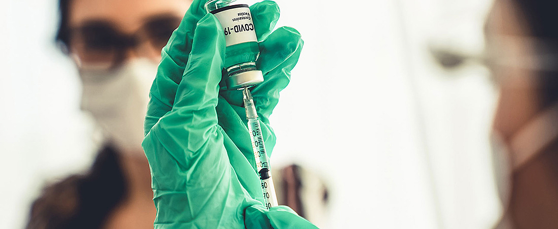 Eine Ärztin zieht eine Spritze mit Coronaimpfstoff auf